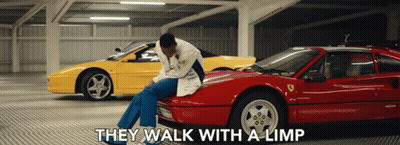 A Man Sits On The Hood Of A Red Sports Car With The Words " They Walk With A Limp " Above Him GIF