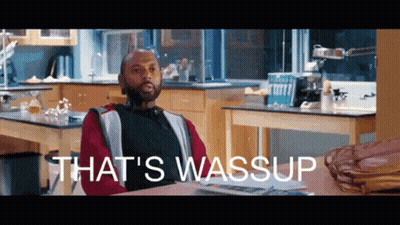 A Man Sitting At A Desk In A Kitchen With The Words That 'S Wassup On The Bottom GIF