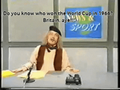 A Man Sitting At A Desk In Front Of A News And Sport Sign GIF