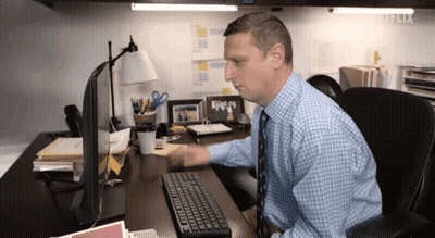 A Man Sitting At A Desk Using A Computer With Netflix Written On The Corner GIF