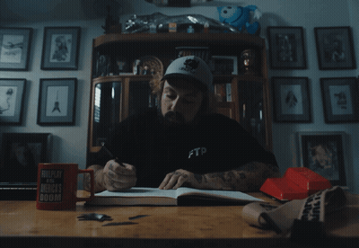A Man Sitting At A Desk Wearing A Black Ftp Shirt GIF
