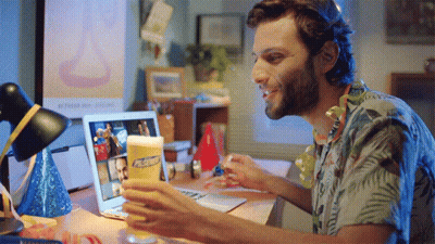 A Man Sitting At A Desk With A Laptop And A Glass Of Pabst Beer In Front Of Him GIF