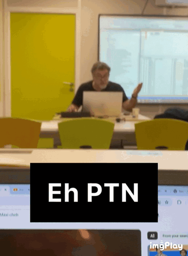 A Man Sitting At A Desk With A Laptop And A Sign That Says Eh Ptn On It GIF