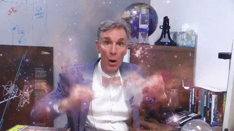 A Man Sitting At A Desk With A National Geographic Poster In The Background GIF