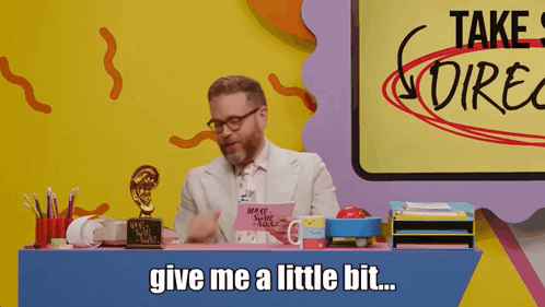 A Man Sitting At A Desk With A Sign That Says Take Direct On It GIF