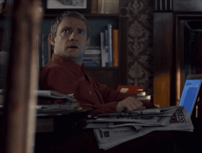 A Man Sitting At A Desk With A Stack Of Newspapers And A Laptop With The Word Press On It GIF