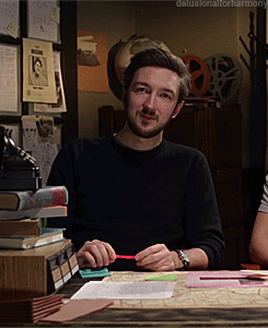 A Man Sitting At A Desk With The Words Delusionalforharmony Written On The Bottom GIF