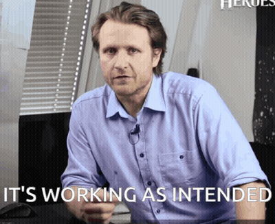 A Man Sitting At A Desk With The Words " It 'S Working As Intended " Behind Him GIF