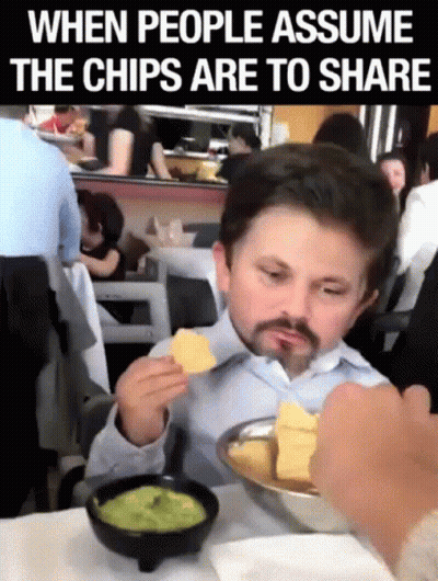 A Man Sitting At A Table Eating Chips And Guacamole GIF