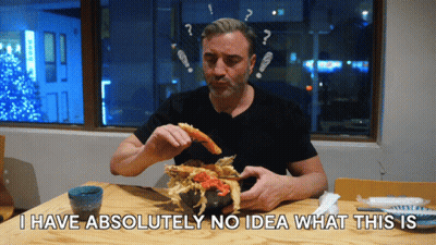 A Man Sitting At A Table Eating Food With The Words I Have Absolutely No Idea What This Is GIF