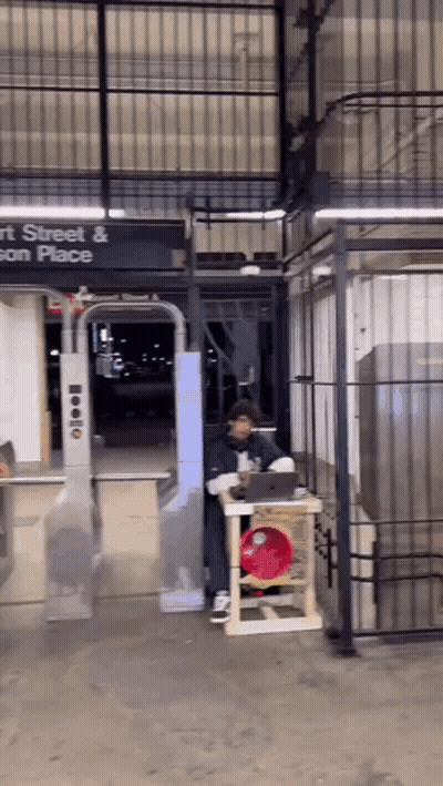 A Man Sitting At A Table In Front Of A Sign That Says Street And Son Place GIF