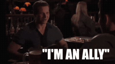 A Man Sitting At A Table Says " I 'M An Ally " While Talking To Another Man GIF