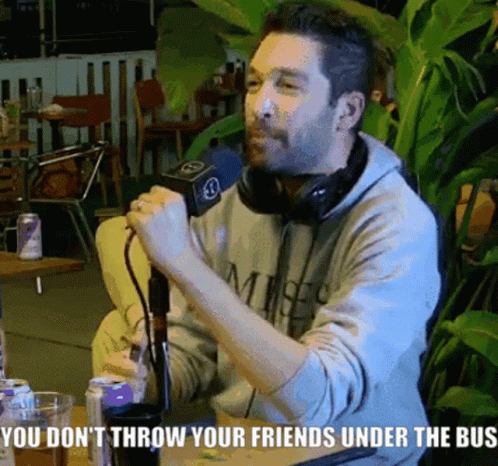 A Man Sitting At A Table Talking Into A Microphone With The Words You Do N't Throw Your Friends Under GIF