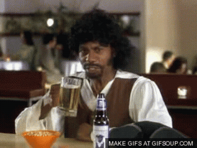 A Man Sitting At A Table With A Bottle Of Budweiser GIF