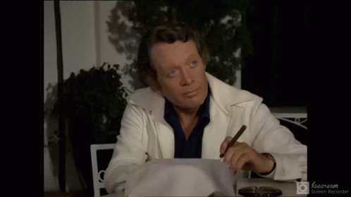 A Man Sitting At A Table With A Cigar And The Words Et Alors Written Below Him GIF
