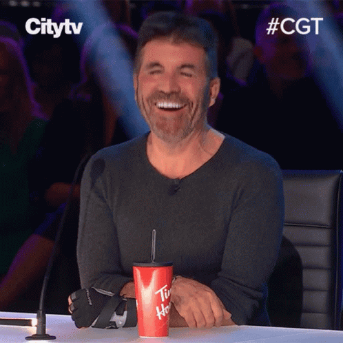 A Man Sitting At A Table With A Cup That Says Tim Hortons GIF