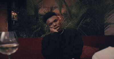 A Man Sitting At A Table With A Glass Of Wine GIF