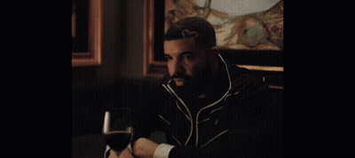 A Man Sitting At A Table With A Glass Of Wine In His Hand GIF
