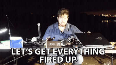 A Man Sitting At A Table With A Laptop And A Sign That Says 8:44 GIF