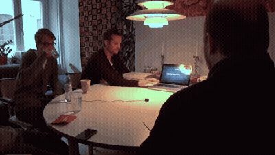 A Man Sitting At A Table With A Laptop That Says ' Macbook Pro ' On The Screen GIF