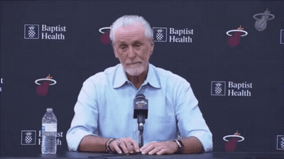 A Man Sitting At A Table With A Microphone In Front Of A Wall That Says Baptist Health GIF