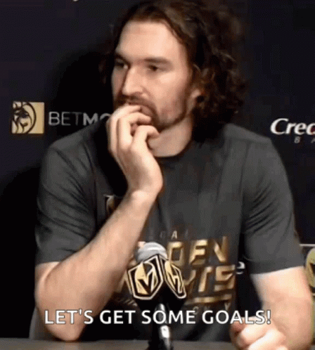 A Man Sitting At A Table With A Microphone In His Hand And The Words Let 'S Get Some Goals Behind Him GIF