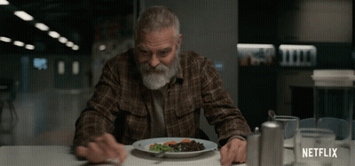 A Man Sitting At A Table With A Plate Of Food And A Netflix Logo On The Bottom GIF