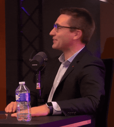 A Man Sitting At A Table With A Shure Microphone GIF
