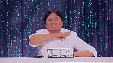 A Man Sitting At A Table With A Sign That Says Kimmy Jong-Un On It GIF
