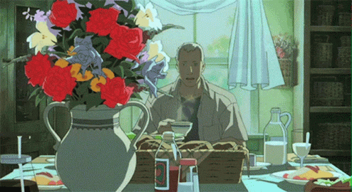 A Man Sitting At A Table With A Vase Of Flowers And A Bottle Of Ketchup GIF