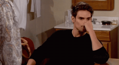 A Man Sitting At A Table With His Hand On His Face And The Word Global On The Bottom GIF