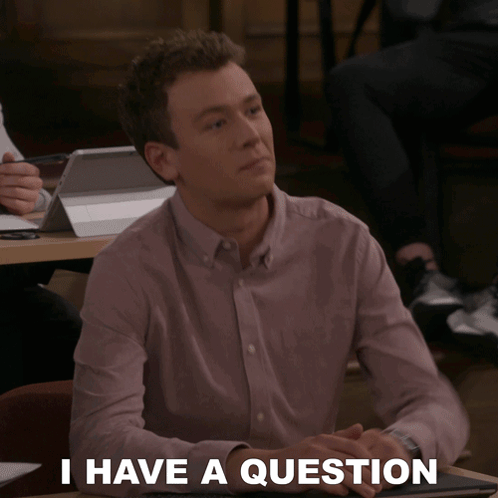 A Man Sitting At A Table With The Words " I Have A Question " On The Bottom GIF