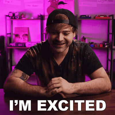 A Man Sitting At A Table With The Words " I 'M Excited " Written On The Screen GIF