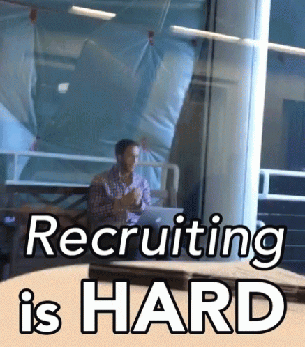 A Man Sitting At A Table With The Words Recruiting Is Hard Written On It GIF