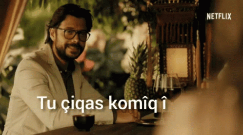 A Man Sitting At A Table With The Words Tu Ciqas Komiq I Above Him GIF