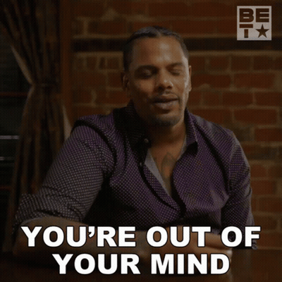 A Man Sitting At A Table With The Words You 'Re Out Of Your Mind Behind Him GIF