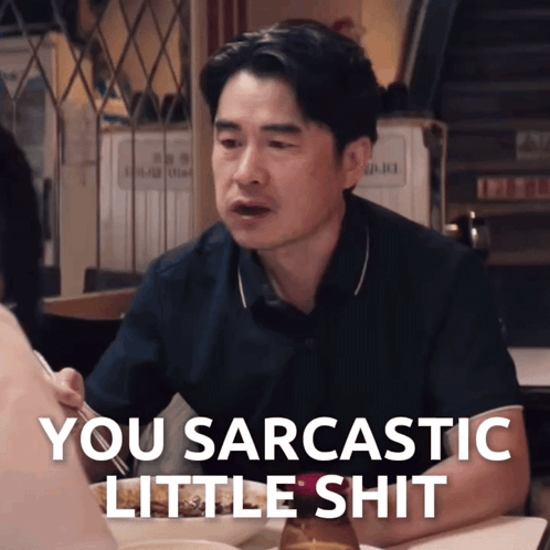 A Man Sitting At A Table With The Words You Sarcastic Little Shit Written Below Him GIF