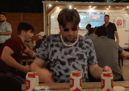 A Man Sitting At A Table With Three Cans Of Lone Star Beer On It GIF
