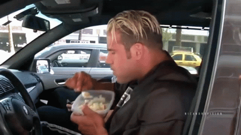 A Man Sitting In A Car Eating From A Plastic Container With The Name Ricardo On The Bottom GIF