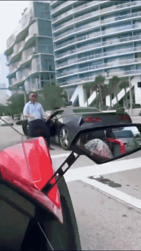 A Man Sitting In A Car Looking At Another Car In A Rear View Mirror GIF