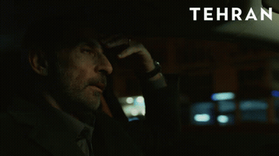 A Man Sitting In A Car With Tehran Written On The Bottom GIF
