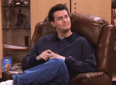 A Man Sitting In A Chair Laughing With His Mouth Open GIF
