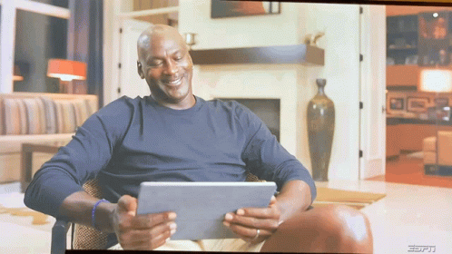 A Man Sitting In A Chair Looking At A Tablet With The Espn Logo On The Bottom GIF