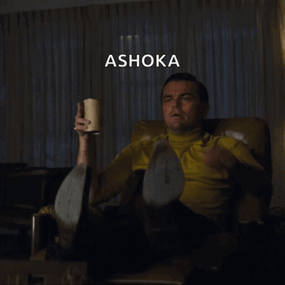 A Man Sitting In A Chair Pointing At Something With The Word Ashoka Written Above Him GIF