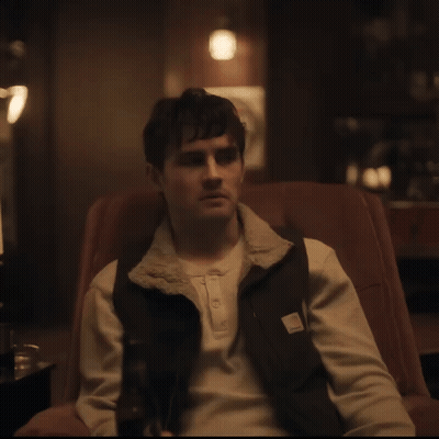 A Man Sitting In A Chair Wearing A Carhartt Vest GIF