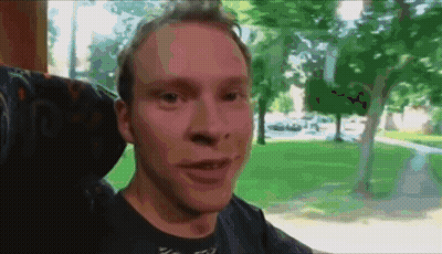 A Man Sitting In A Chair With A Blurred Background Of Trees GIF