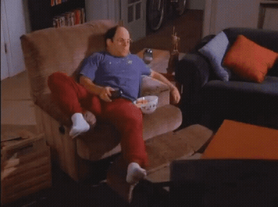 A Man Sitting In A Chair With A Bowl Of Popcorn On His Lap GIF