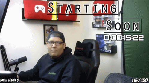 A Man Sitting In A Chair With A Sign That Says Starting Soon On It GIF