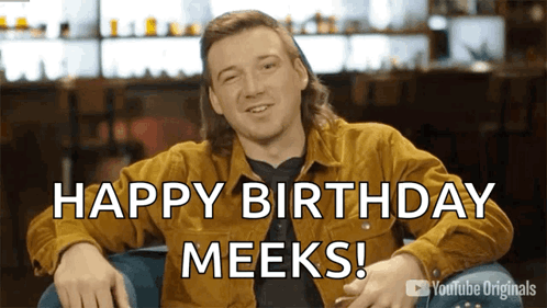 A Man Sitting In A Chair With The Words Happy Birthday Meeks On The Screen GIF
