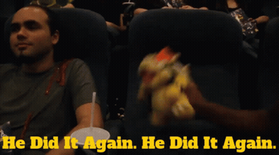 A Man Sitting In A Movie Theater Holding A Stuffed Bowser GIF
